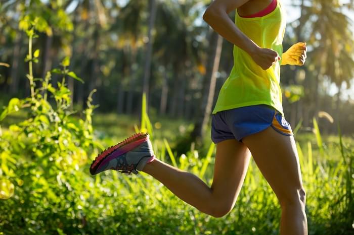 Young fitness woman running at morning tropical forest trail